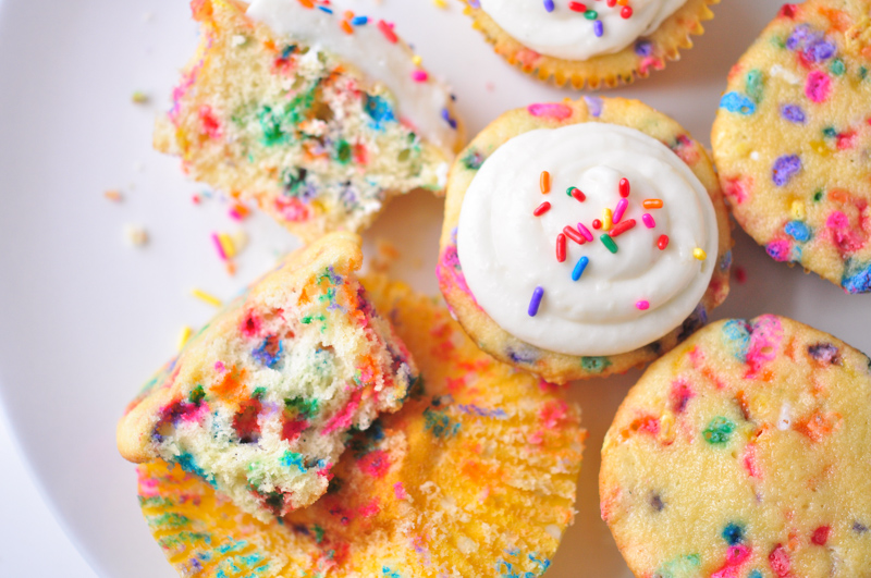 A plate of funfetti cupcakes with rainbow colored sprinkles. 