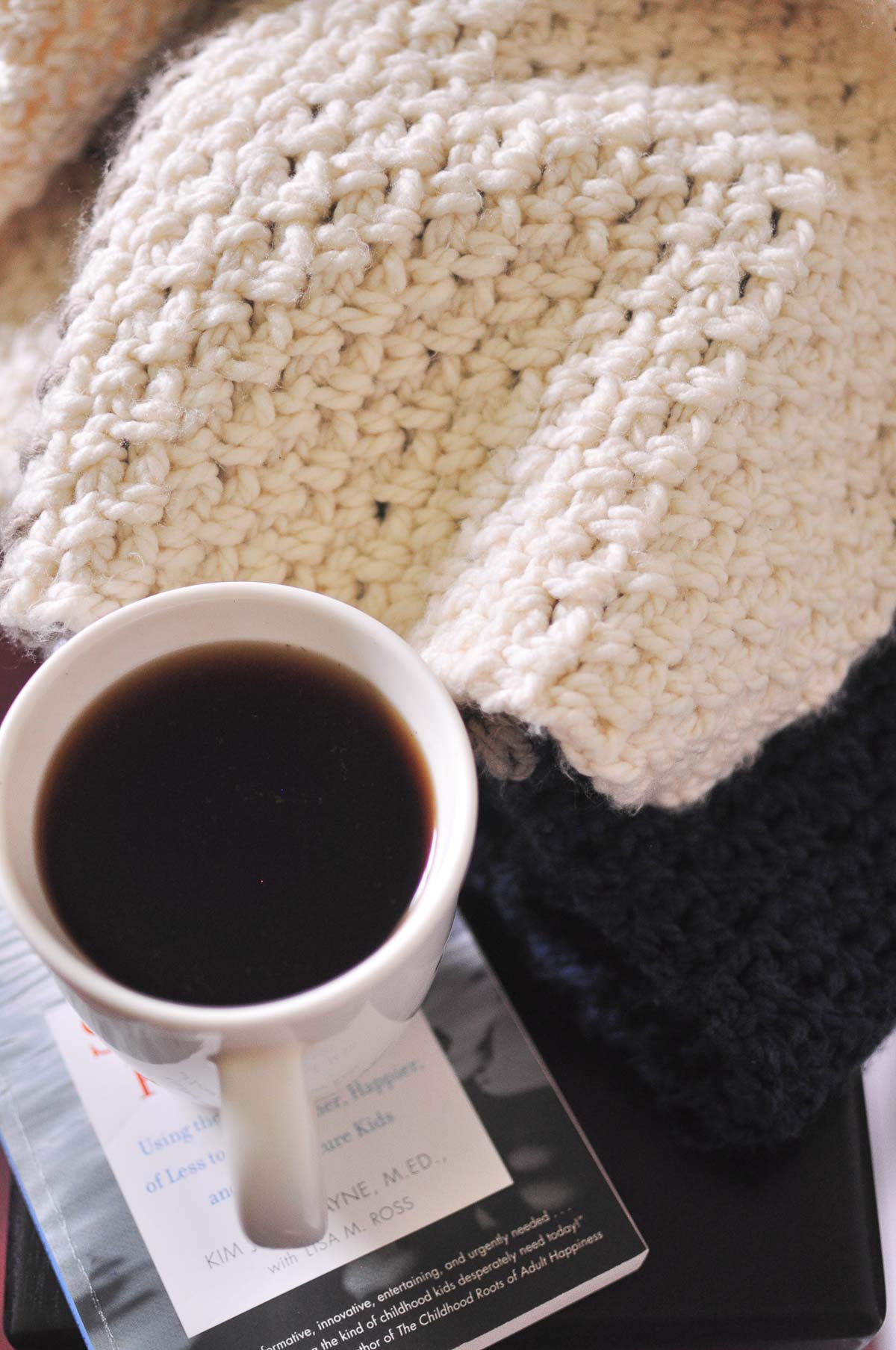 A cup of coffee, book and blanket.