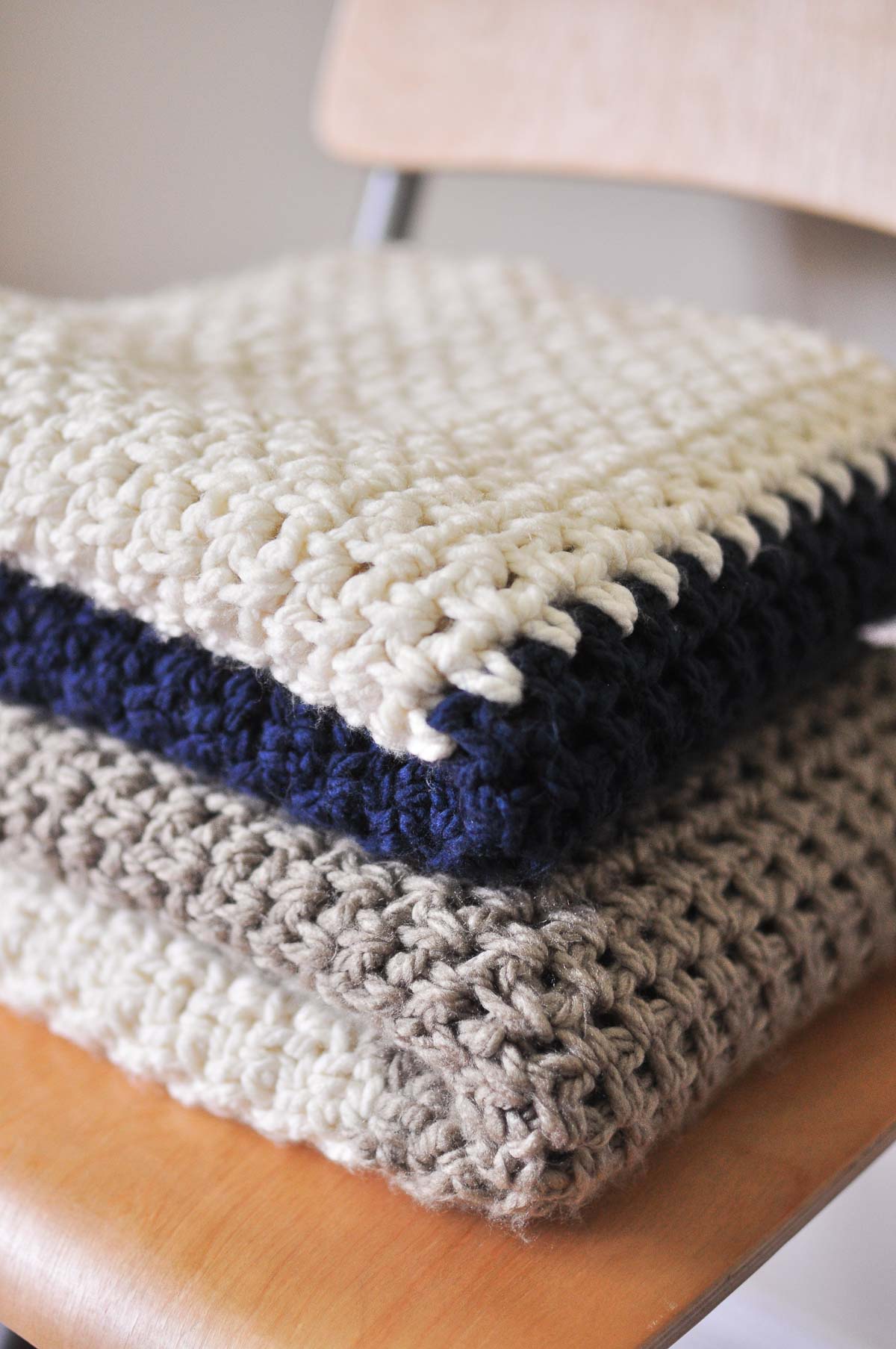 A folded crochet moss stitch blanket on a chair.