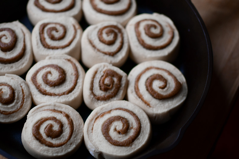 A cast iron skillet with sourdough cinnamon rolls that have doubled in size and are ready to bake. 