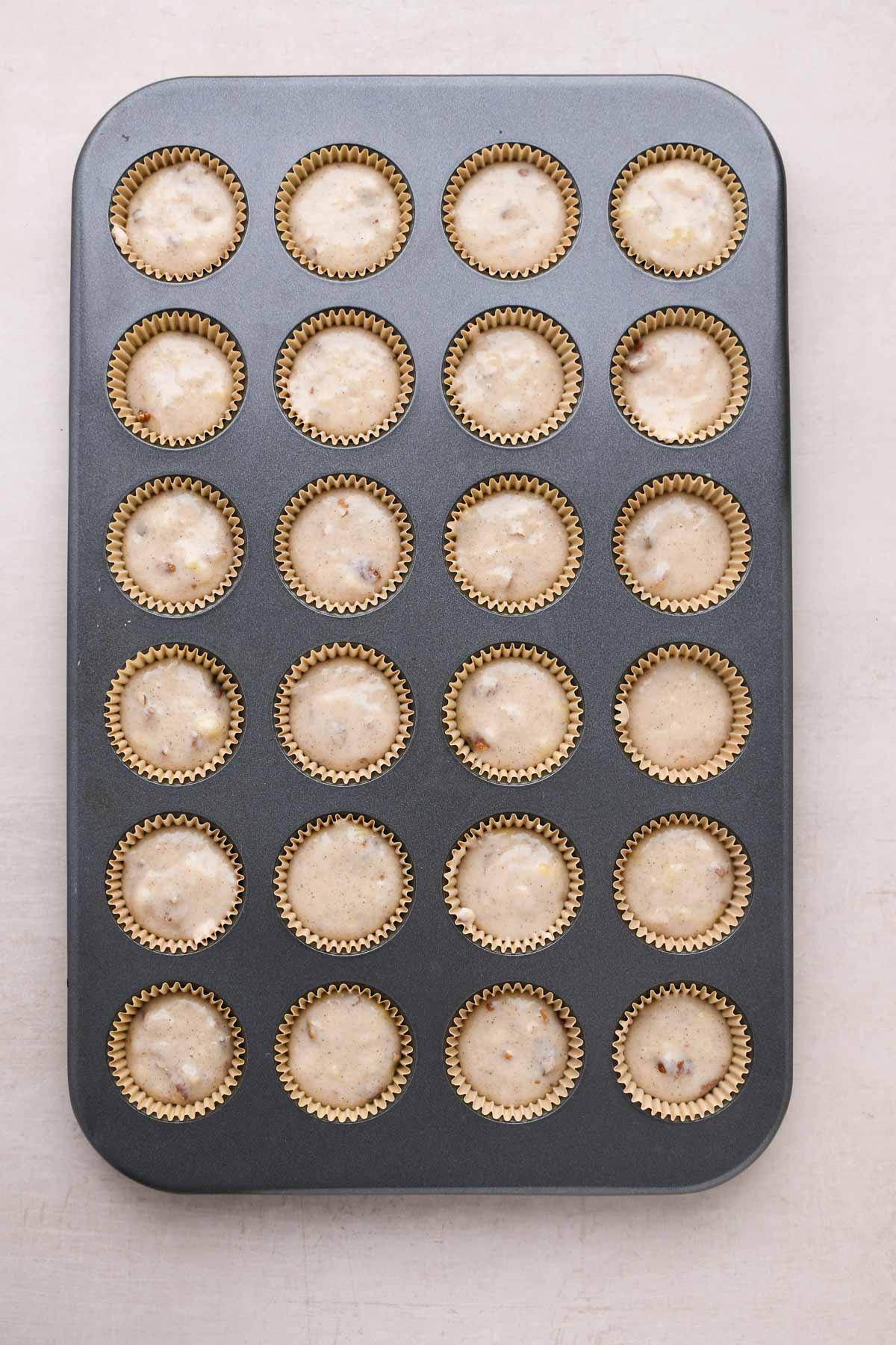 A mini muffin pan filled 3/4 of the way with banana nut batter.