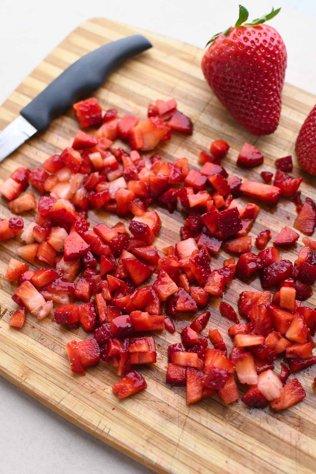 A chopping board with small strawberry pieces