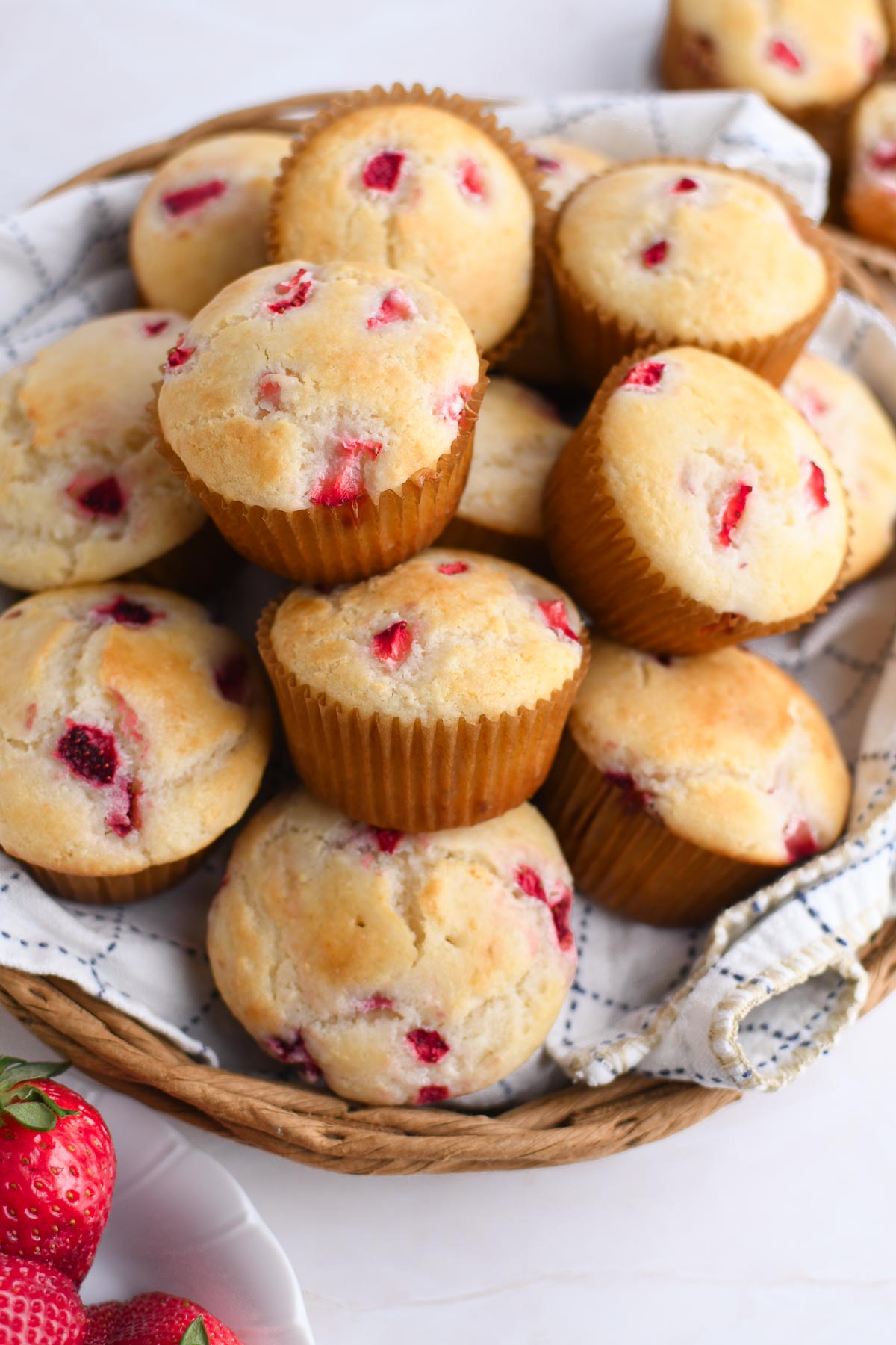 A close up of a basket of strawberry cream cheese muffins