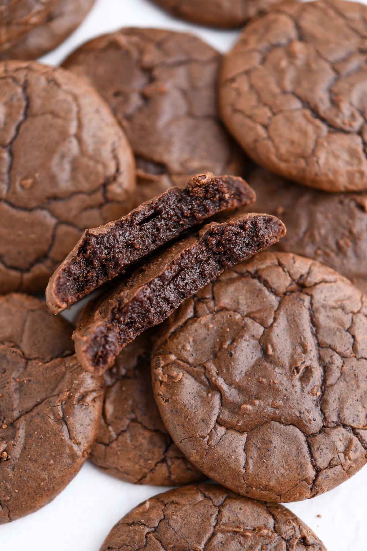 Several brownie cookies with one broken open to show the inside of the cookie texture. 