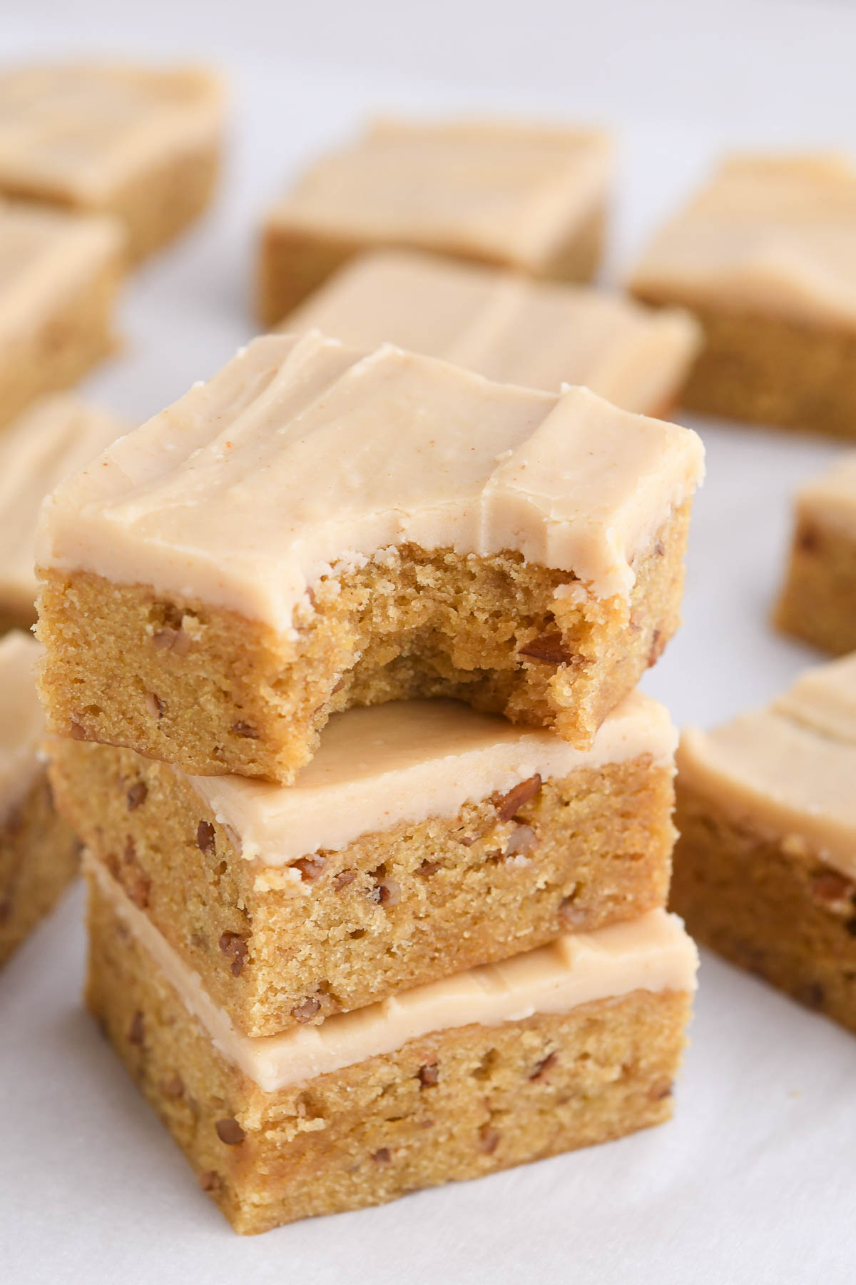 A close up shot of a stack of banana blondies with buttermilk brown butter fudge frosting. 