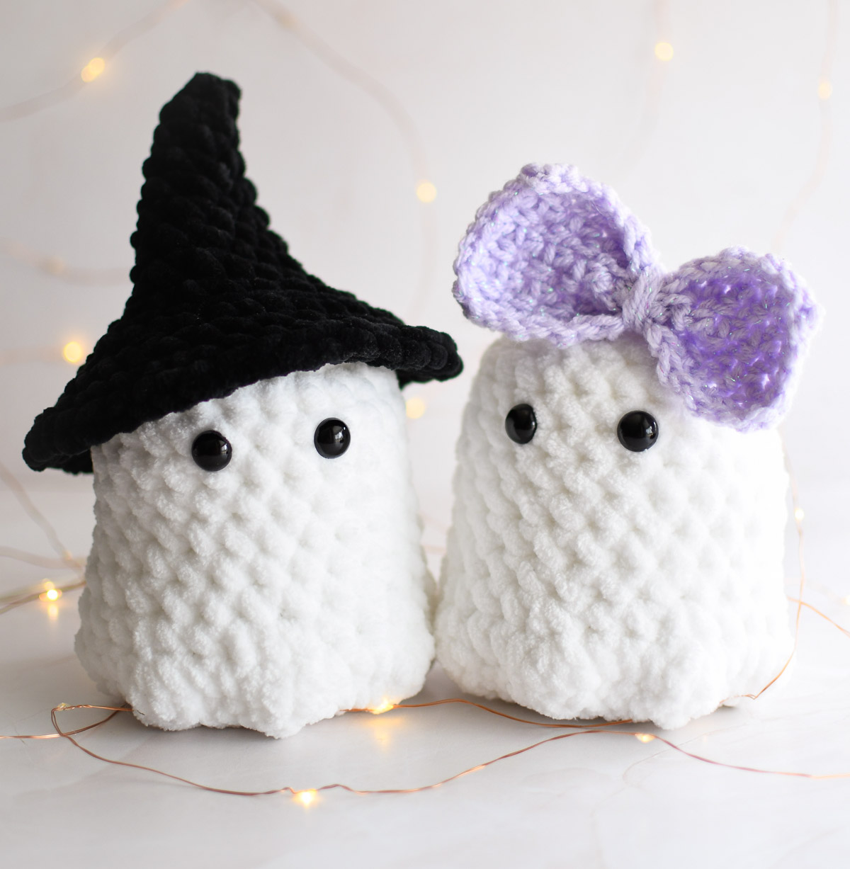 Two Ghost Crochet Plushies wearing a witch hat and a lavender bow. 
